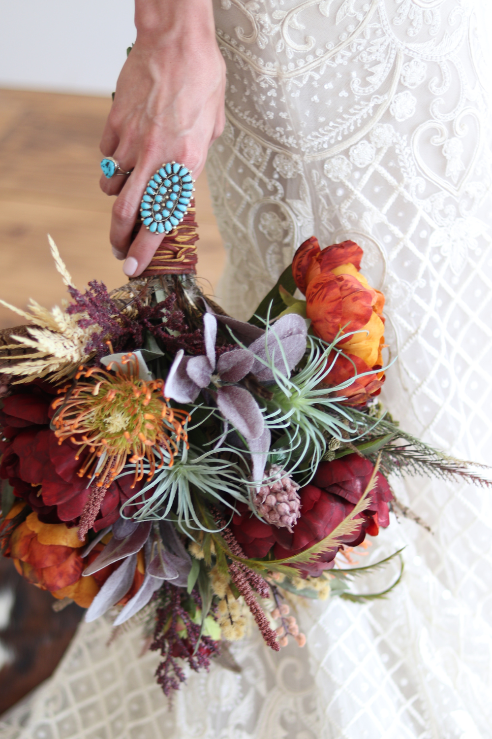 Bride holding a bouquet down at her side wearing rings and other turquoise jewelry from Calli Co. Silver. 
